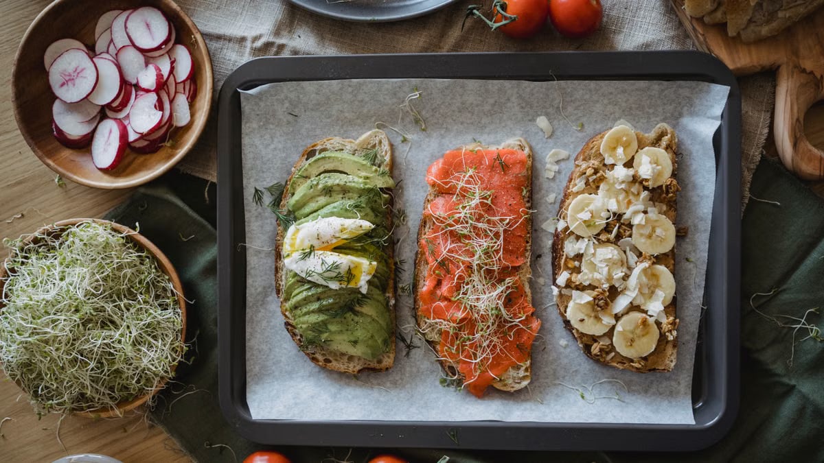 Tray of three assorted open-faced sandwiches with fresh toppings for a delicious meal.