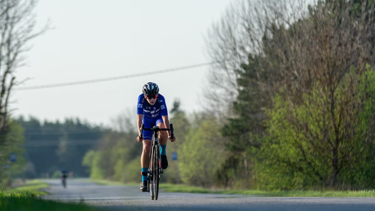 Cyclist competes in race on rural road, capturing speed and endurance in spring scenery.